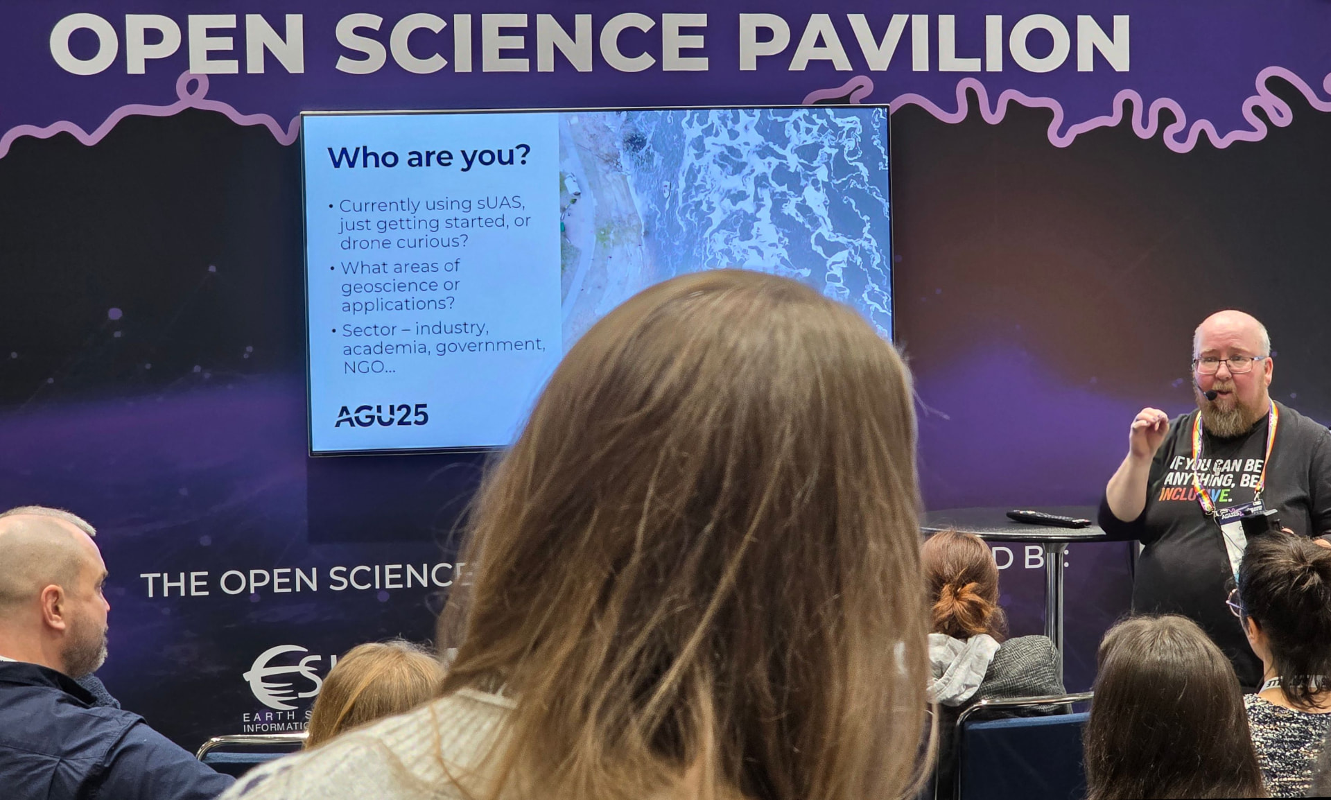 A guide presenting to a seated audience at the AGU25 Open Science Pavilion