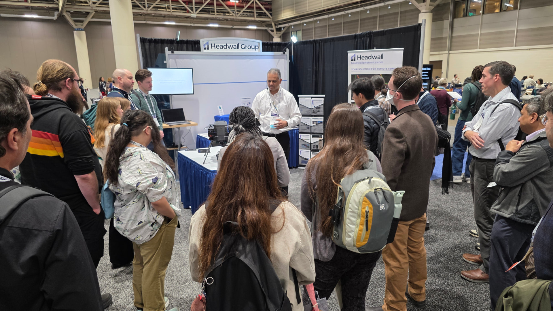 An AGU25 exhibit hall tour group talking with an exhibitor